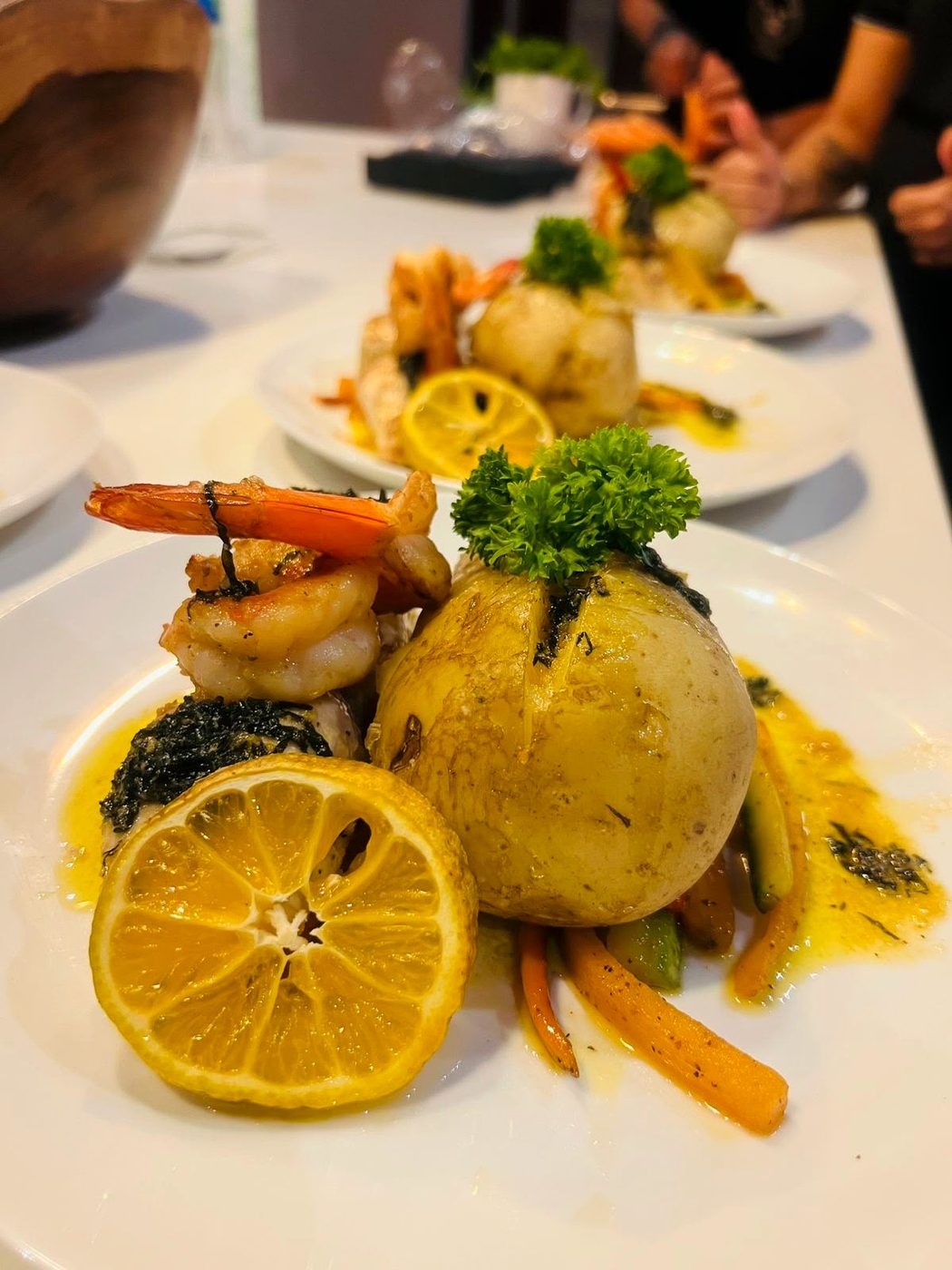 Camarones salteados con papa al horno y limón, emplatados en fila